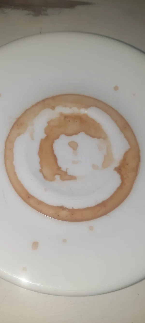 Fondi di caffè su un piattino bianco che disegnano cerchi concentrici